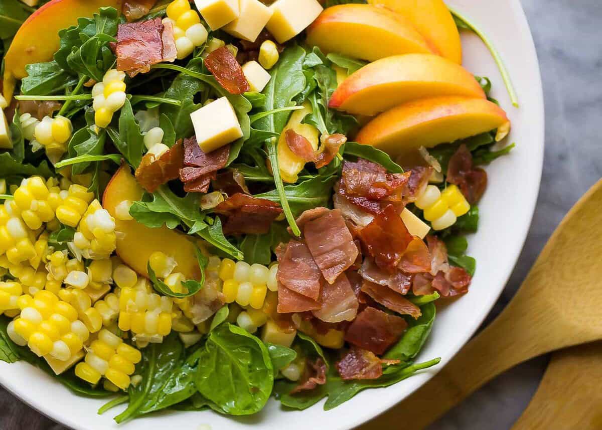 an overhead shot of an assembled summer salad with corn and peaches