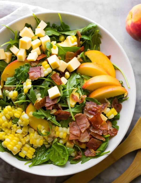 an overhead shot of an assembled summer salad with peaches and corn