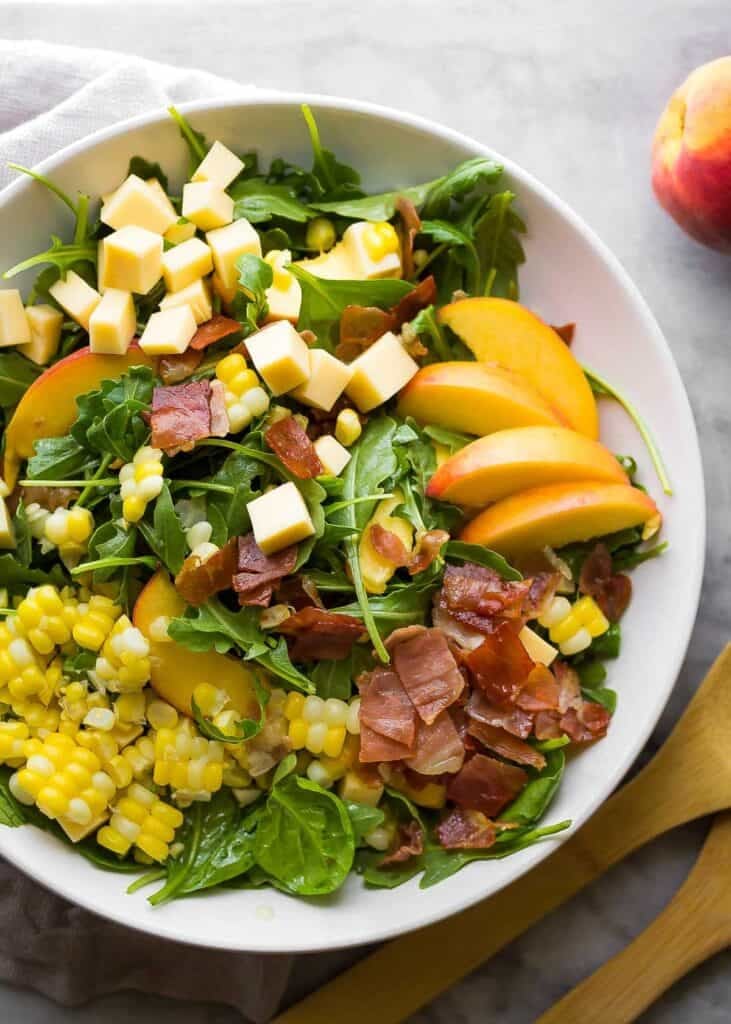 an overhead shot of an assembled summer salad with peaches and corn