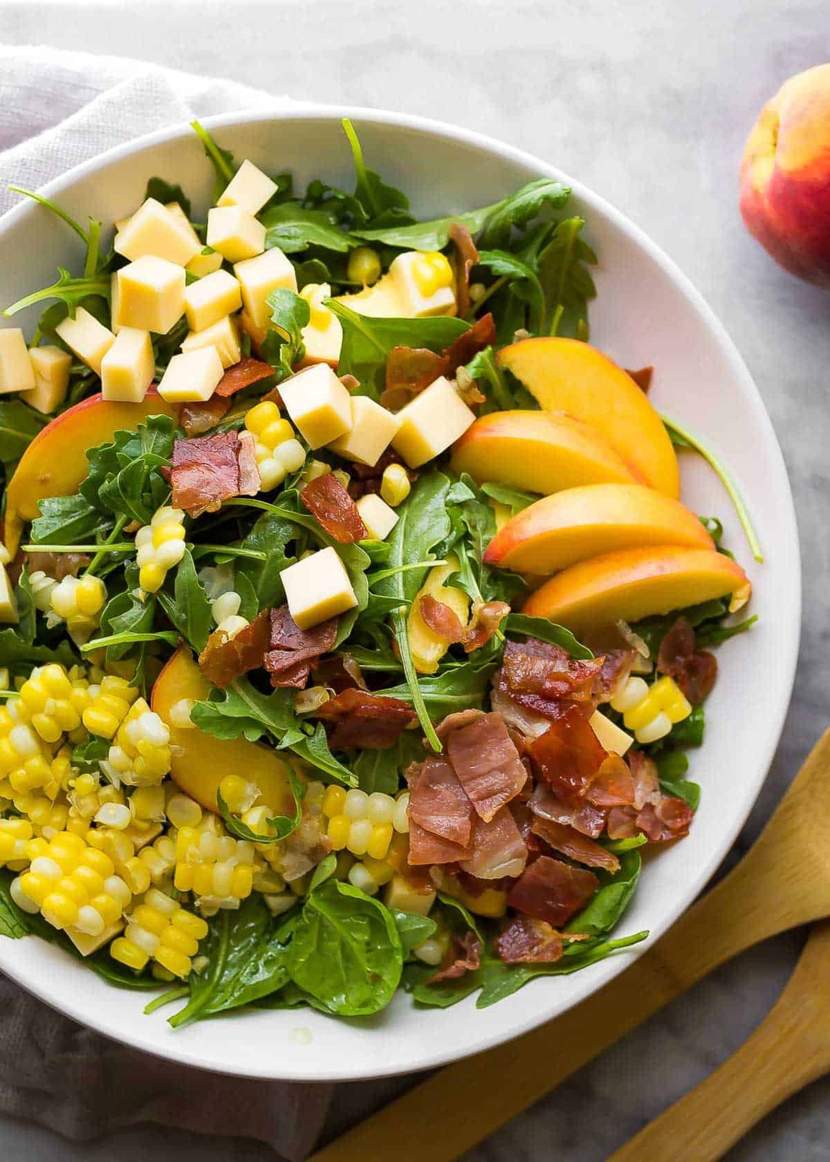 an overhead shot of an assembled summer salad with peaches and corn