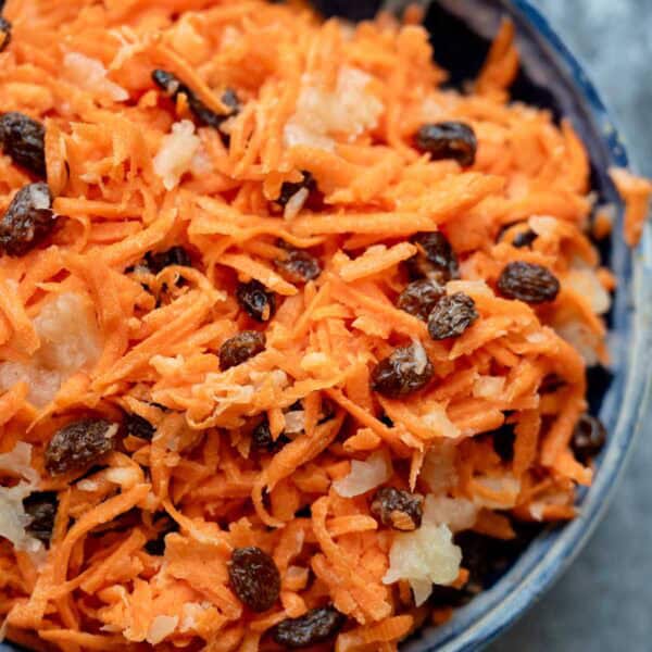 A creamy carrot raisin salad with pineapple chunks and greek yogurt dressing in a bowl