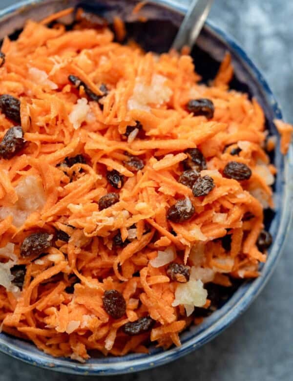 A creamy carrot raisin salad with pineapple chunks and greek yogurt dressing in a bowl