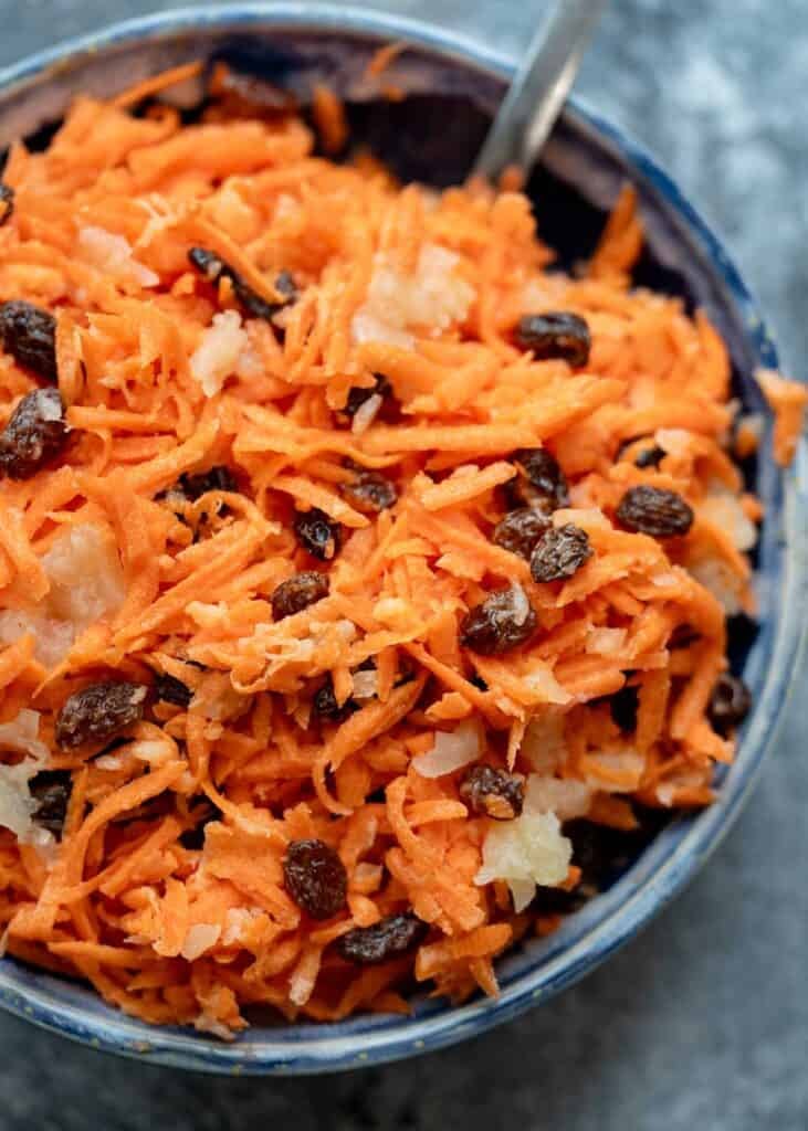 A creamy carrot raisin salad with pineapple chunks and greek yogurt dressing in a bowl