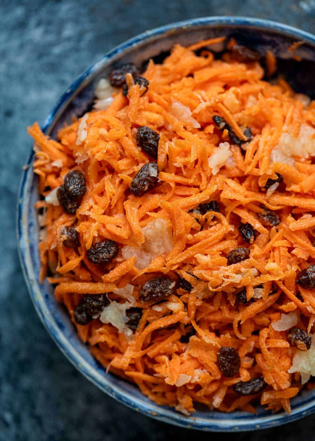 a big bowl full of creamy carrot salad with pineapple and raisins