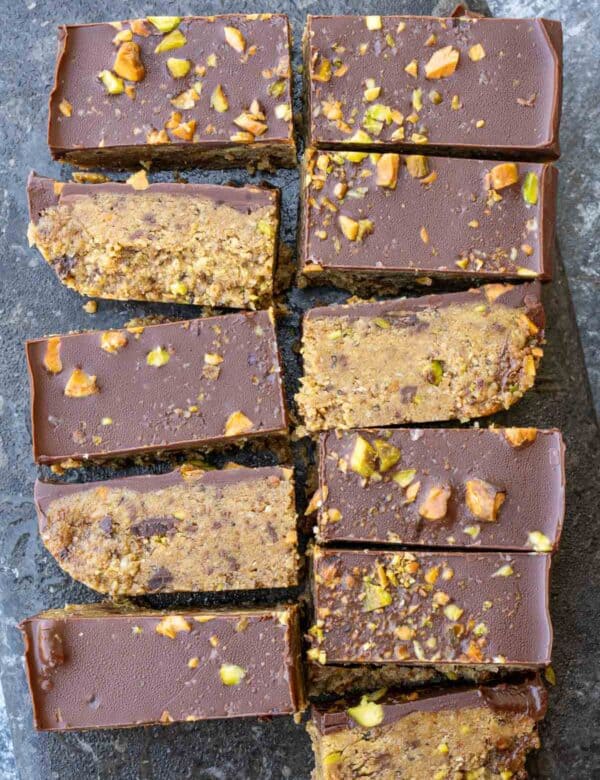 Eleven pistachio bars sliced on the counter, topped with dark chocolate and chopped nuts
