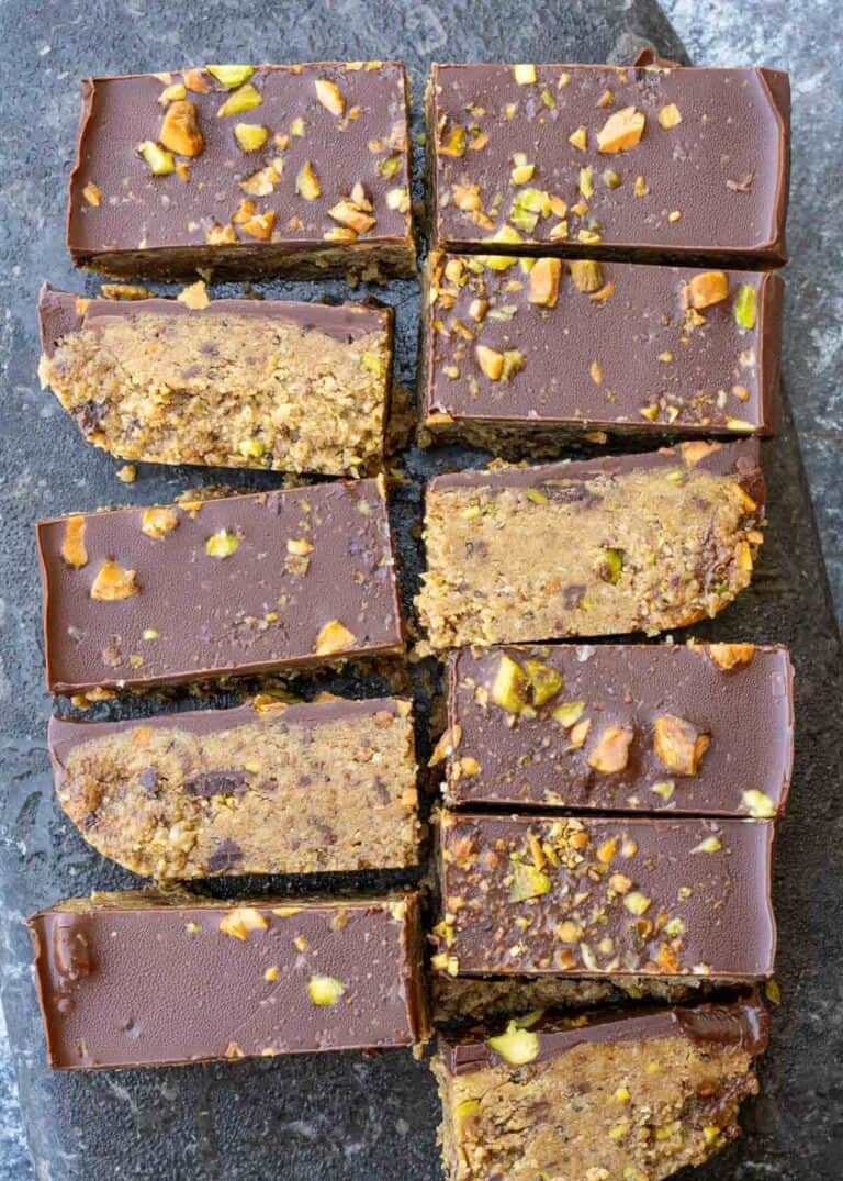 Eleven pistachio bars sliced on the counter, topped with dark chocolate and chopped nuts