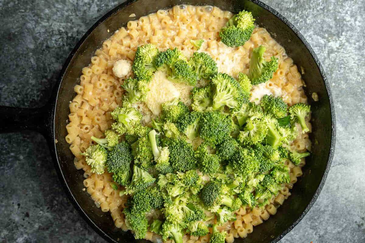 broccoli, butter and parmesan with cooked pasta in a black skillet