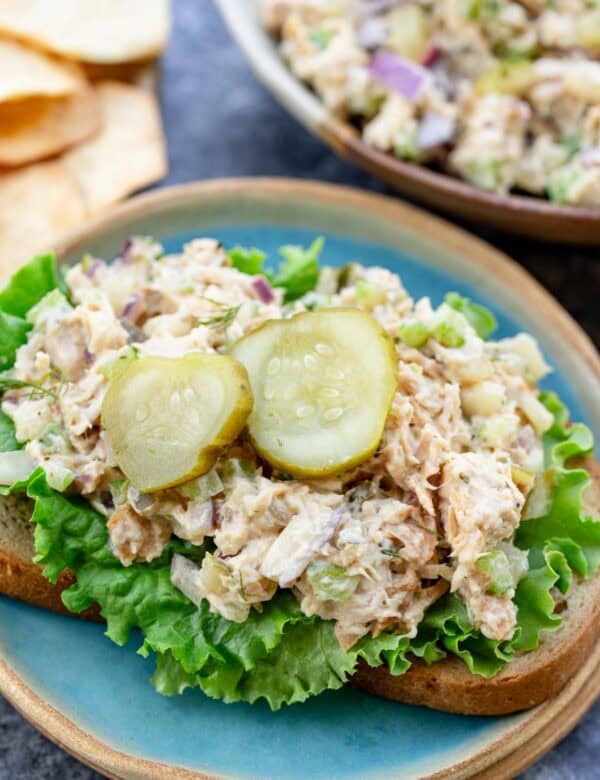 a plate with dill pickle chicken salad and lettuce on a piece of bread