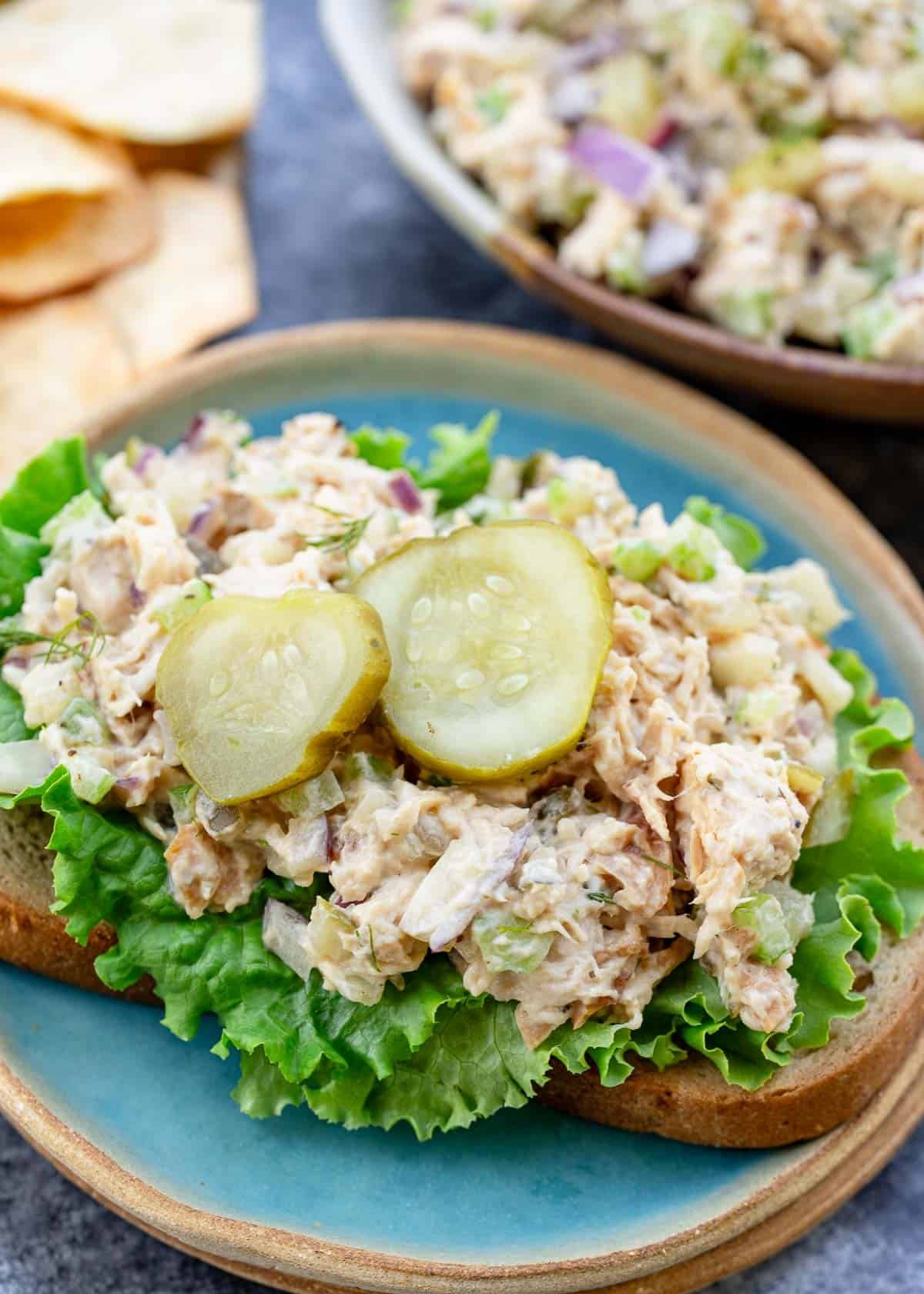 a plate with dill pickle chicken salad and lettuce on a piece of bread