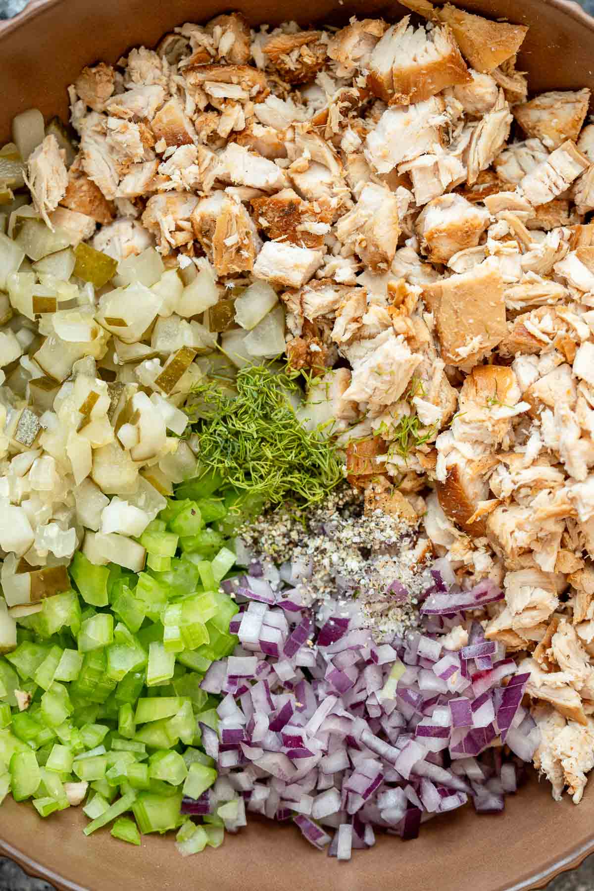 chicken, red onion, celery, pickles, and dill in a bowl