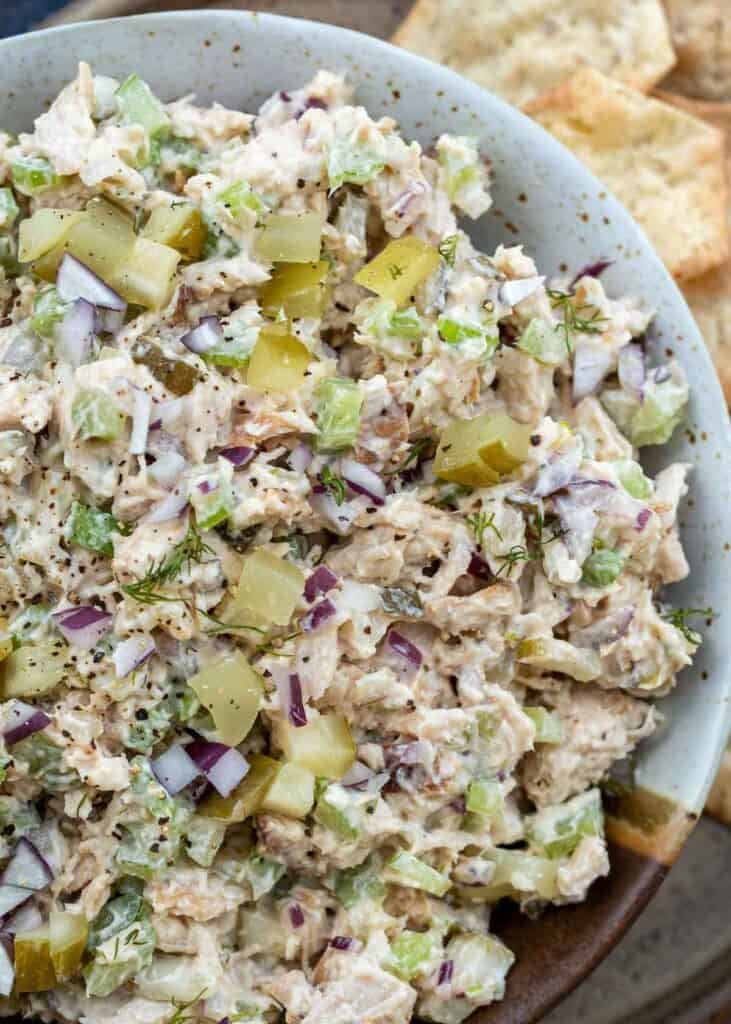 creamy dill pickle chicken salad in a bowl beside crackers for the perfect high-protein lunch idea