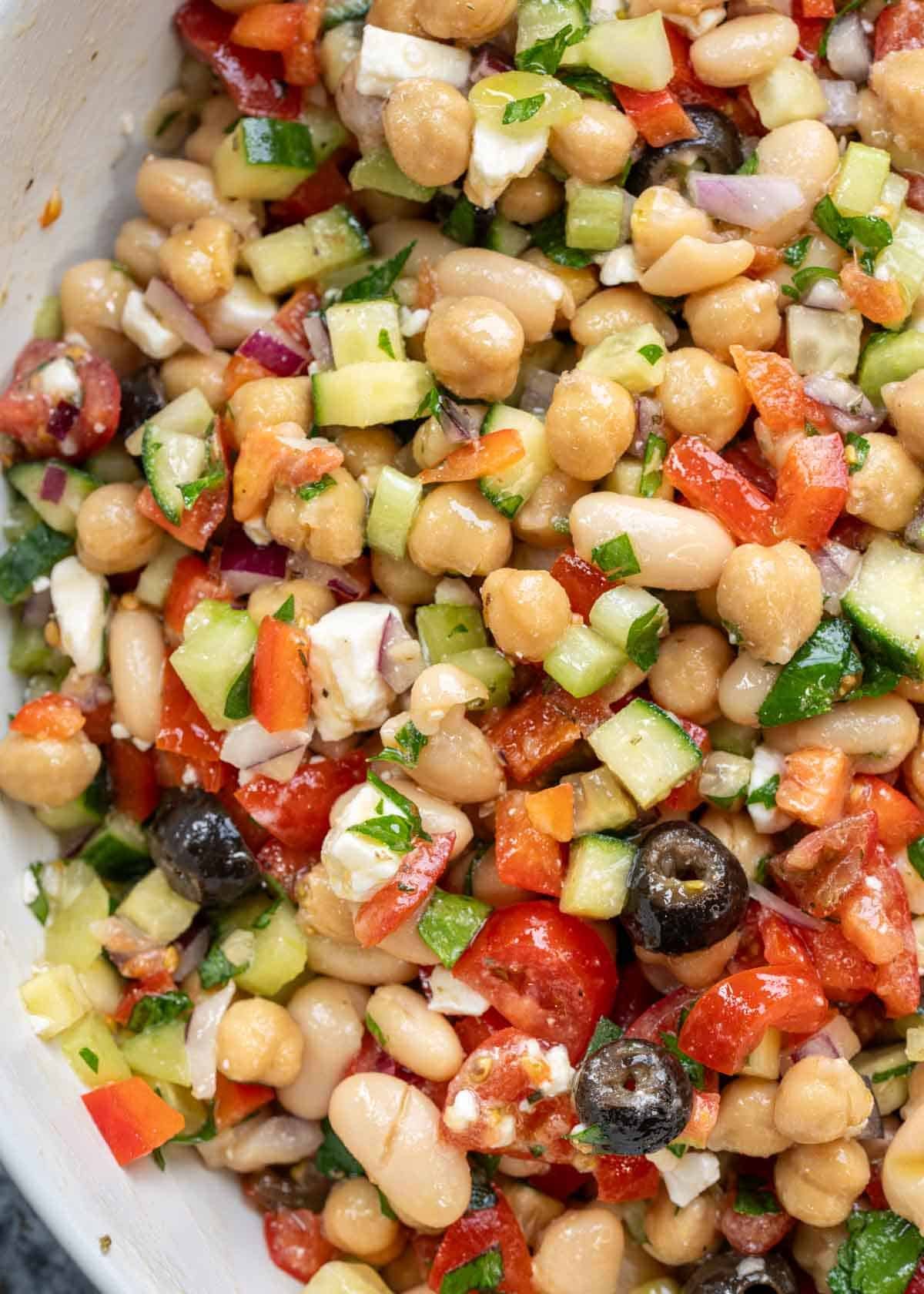 a closeup shot of dense bean salad in a white bowl