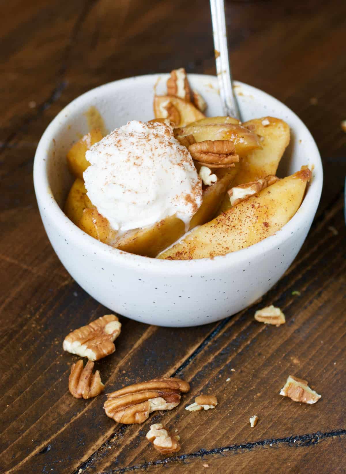 slow cooker apples in a bowl with a scoop of ice cream and a spoon