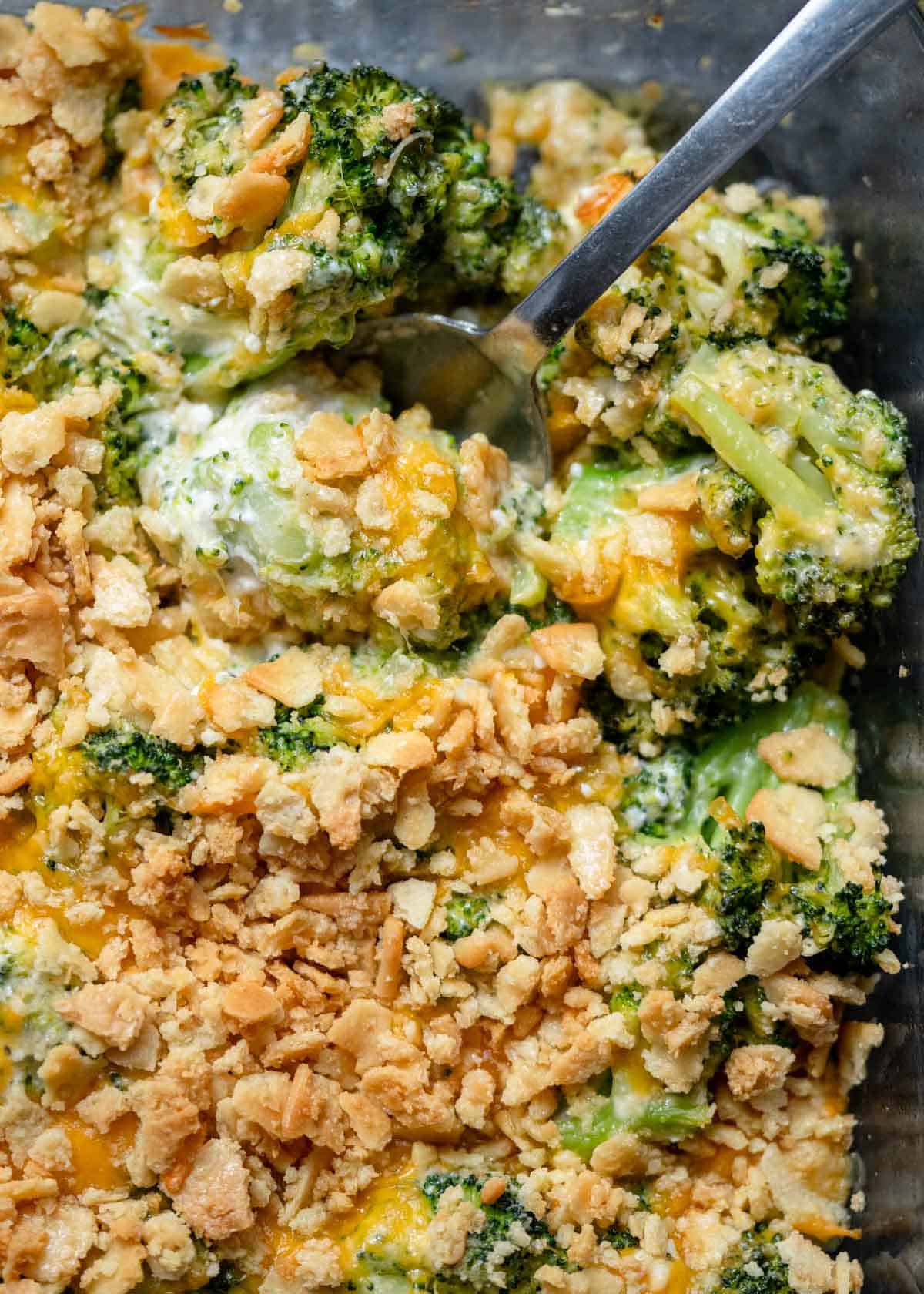 an overhead shot of a cooked broccoli cheese casserole with a spoon in the dish