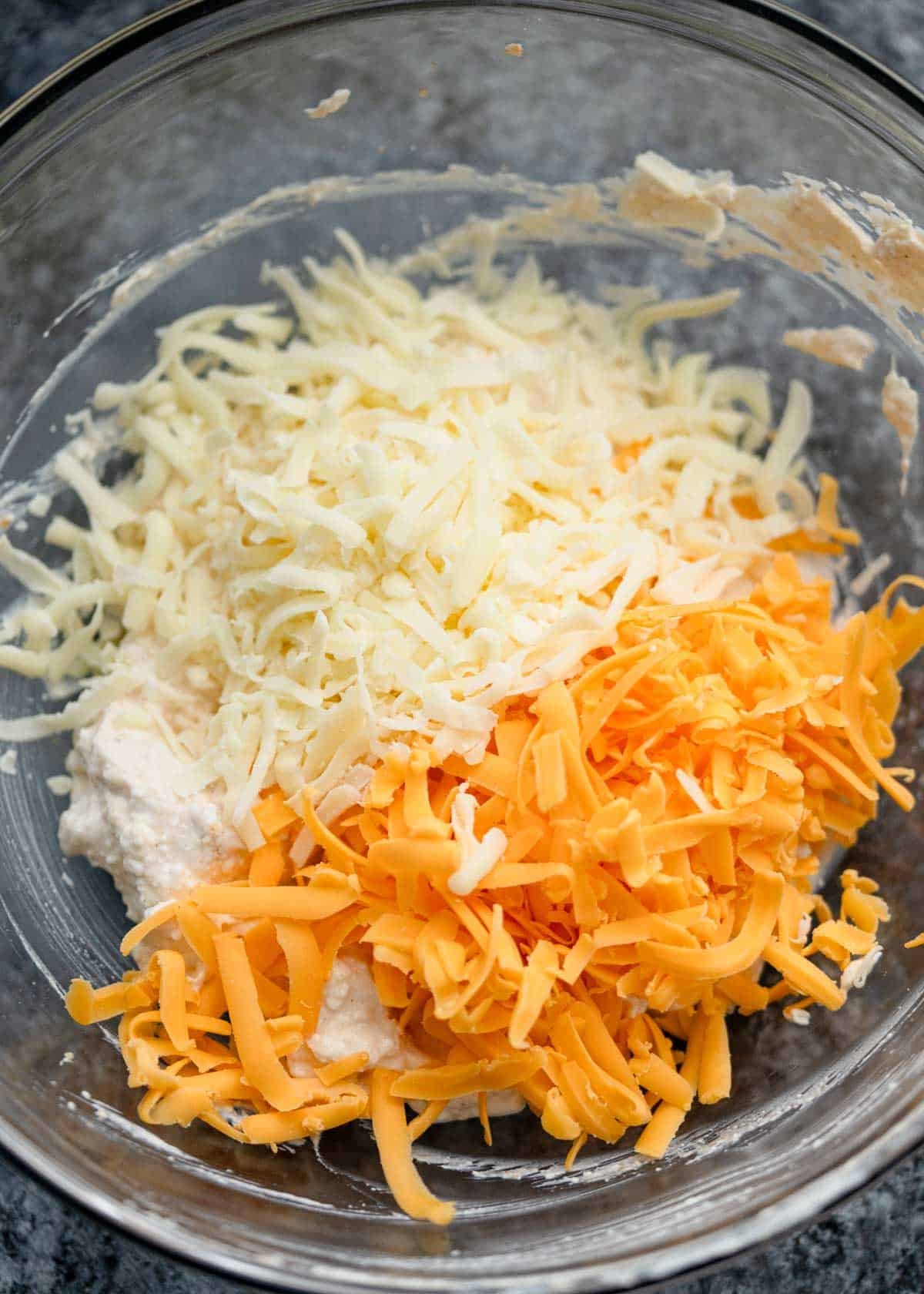 creamy sauce and shredded cheese in a bowl for broccoli cheese casserole