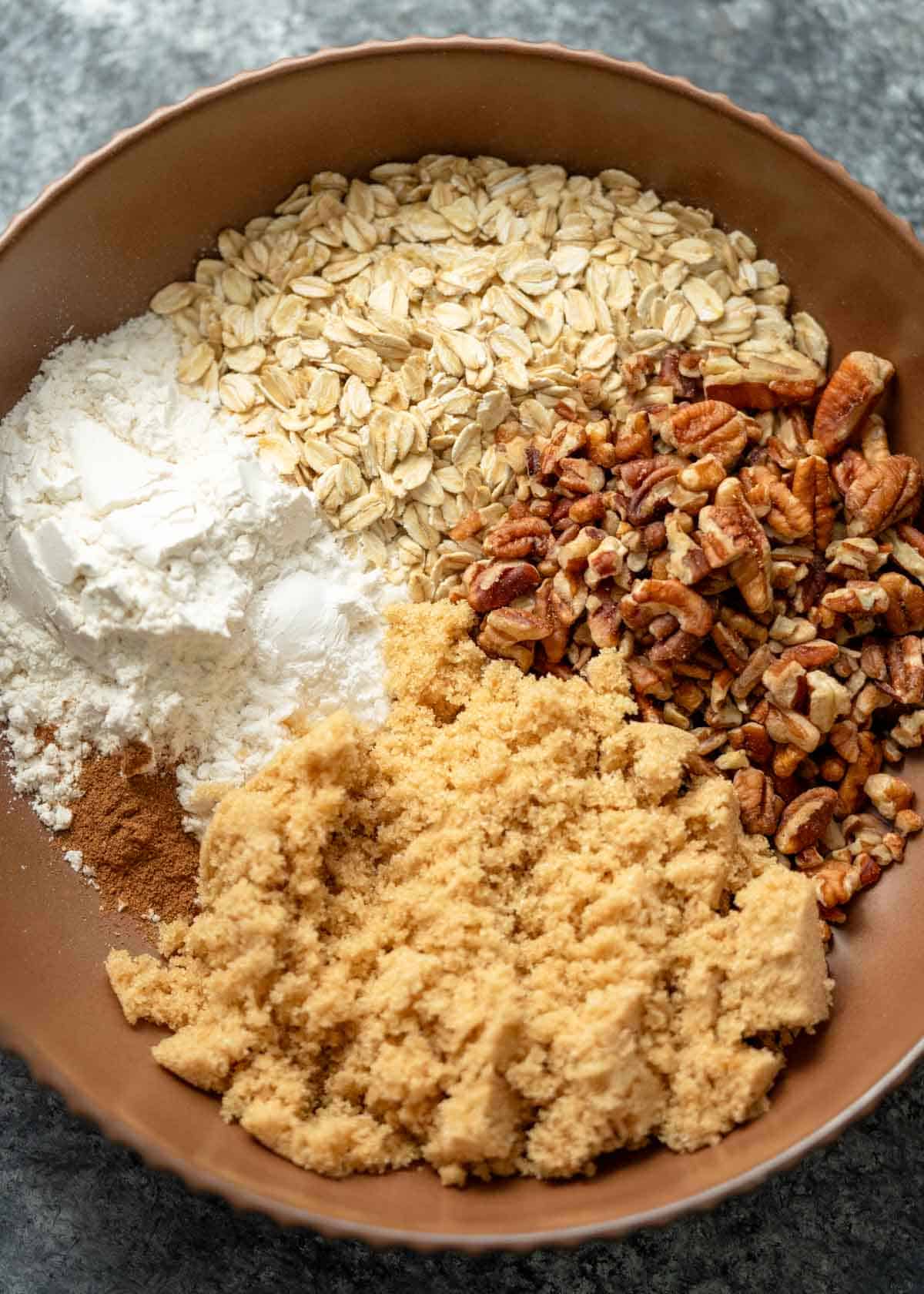 a bowl full of the ingredients for a brown sugar pecan topping for sweet potato casserole