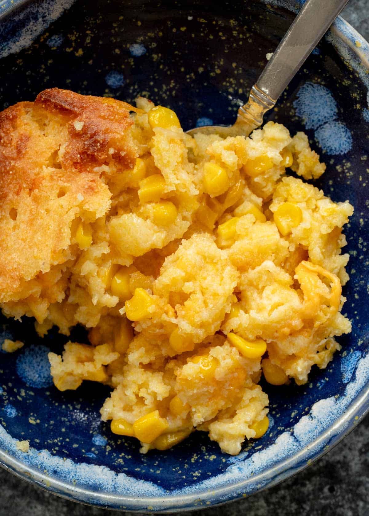a closeup shot of a corn casserole in a blue bowl