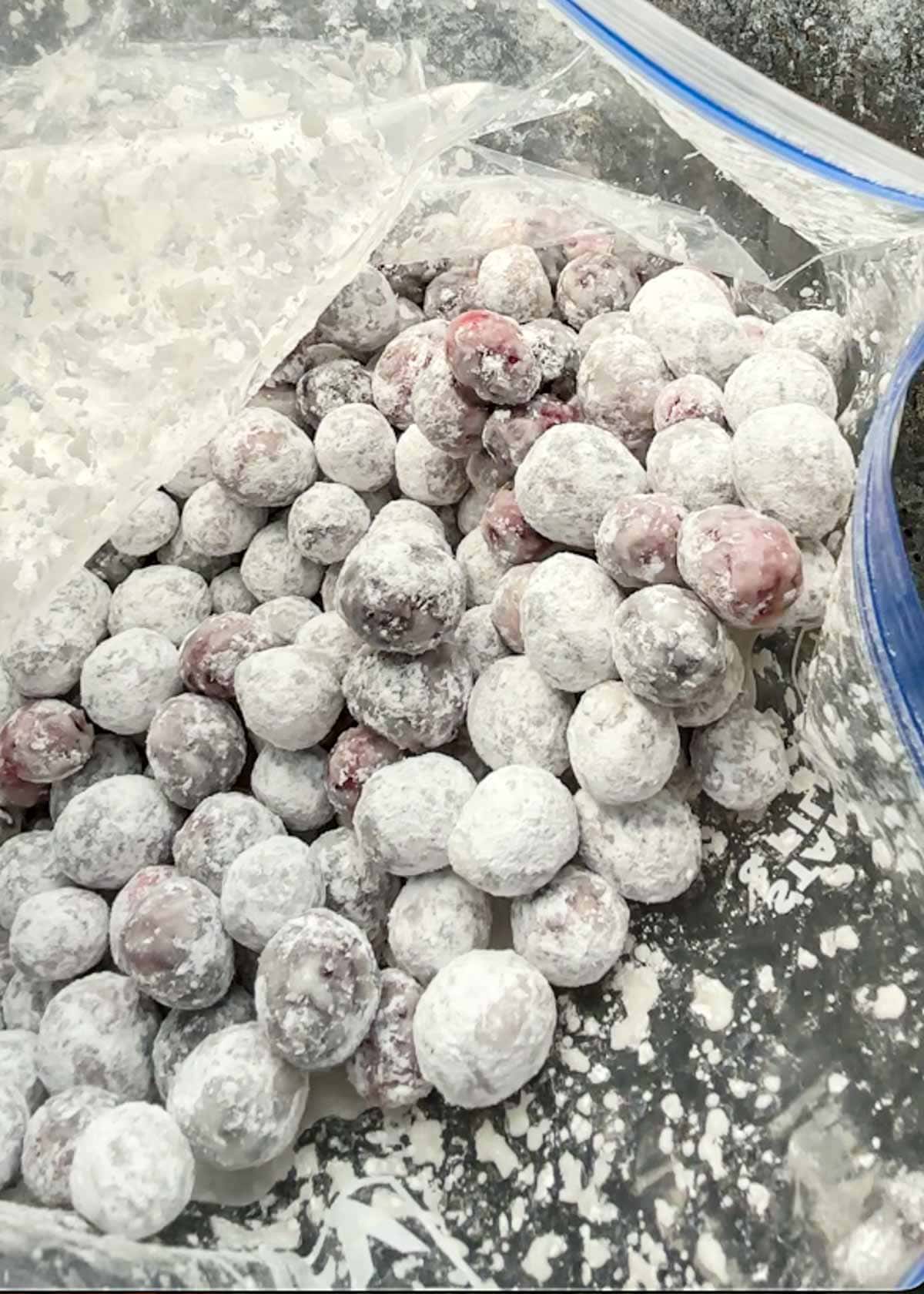 cranberries and powdered sugar in a bag making candied cranberries