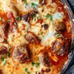 overhead shot showing melty cheese on a meatball bake in a skillet