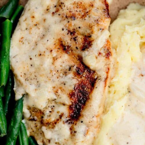 overhead shot of creamy garlic chicken on a plate with potatoes and green beans