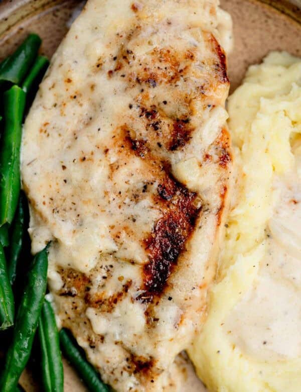 overhead shot of creamy garlic chicken on a plate with potatoes and green beans