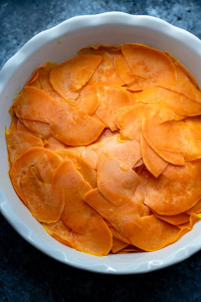 cooked thinly sliced sweet potatoes in a pie pan