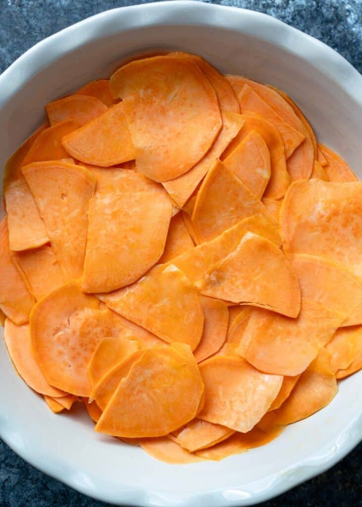 thinly sliced sweet potatoes in a pie pan