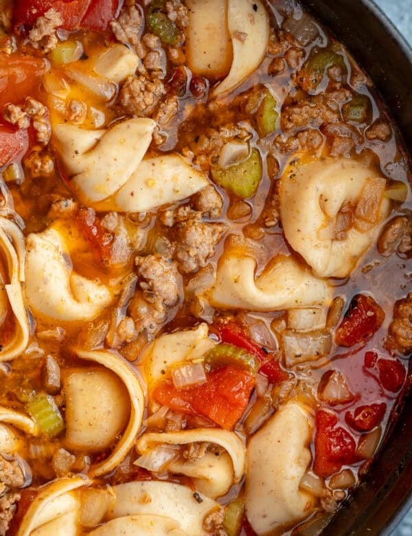 closeup shot of sausage tortellini soup in a pot with tomatoes and vegetables