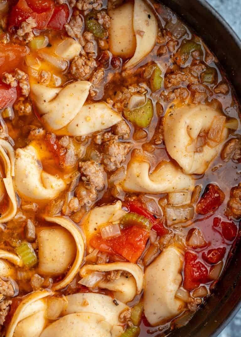 closeup shot of sausage tortellini soup in a pot with tomatoes and vegetables