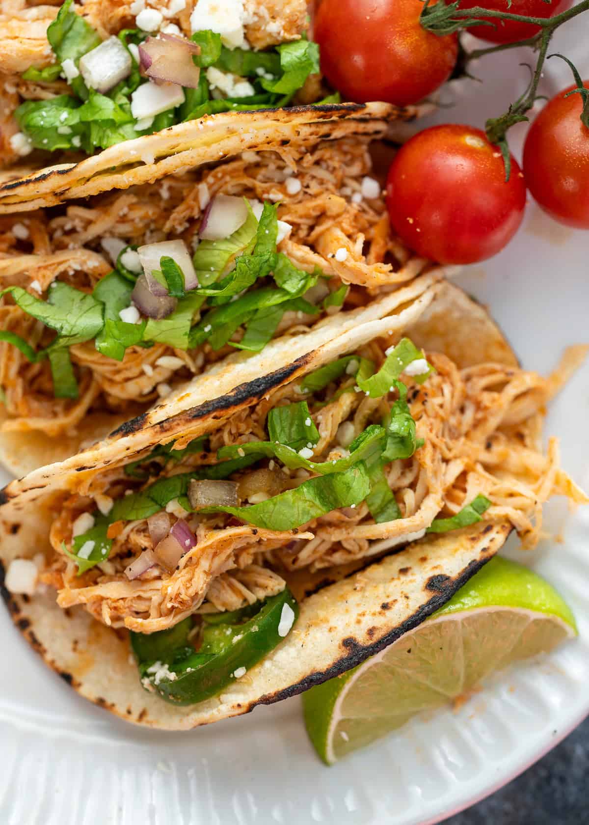 several chicken tinga tacos topped with jalapenos, fresh cilantro, and cotija cheese
