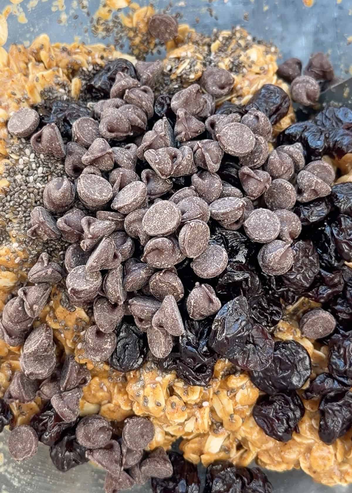 chocolate chips and dried cherries being added to homemade granola bar mix