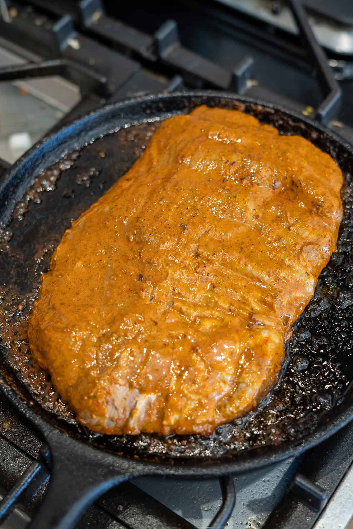 uncooked carne asada in cast iron skillet
