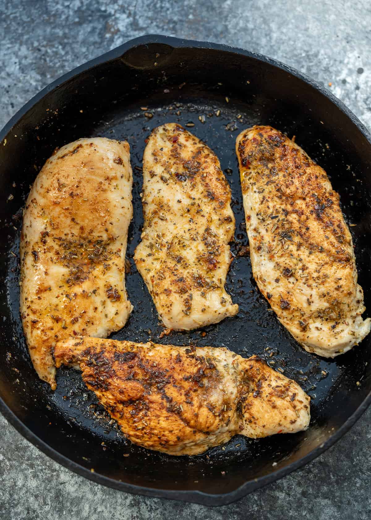 seasoned chicken breasts in a cast iron skillet