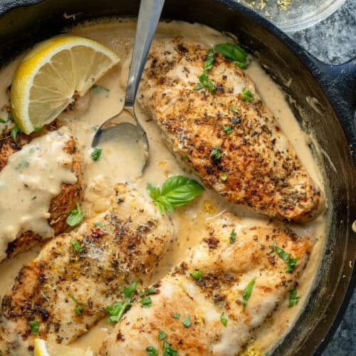 lemon chicken in creamy sauce with a spoon in a cast iron skillet