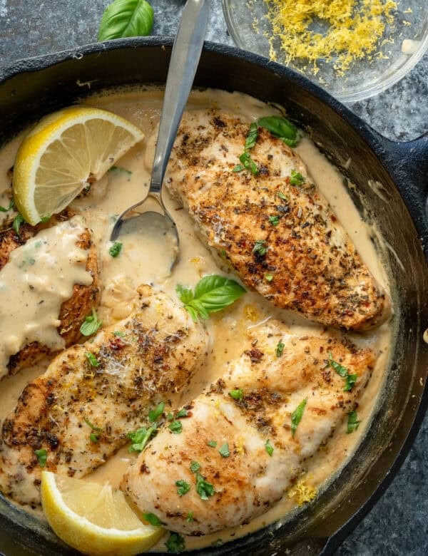 lemon chicken in creamy sauce with a spoon in a cast iron skillet