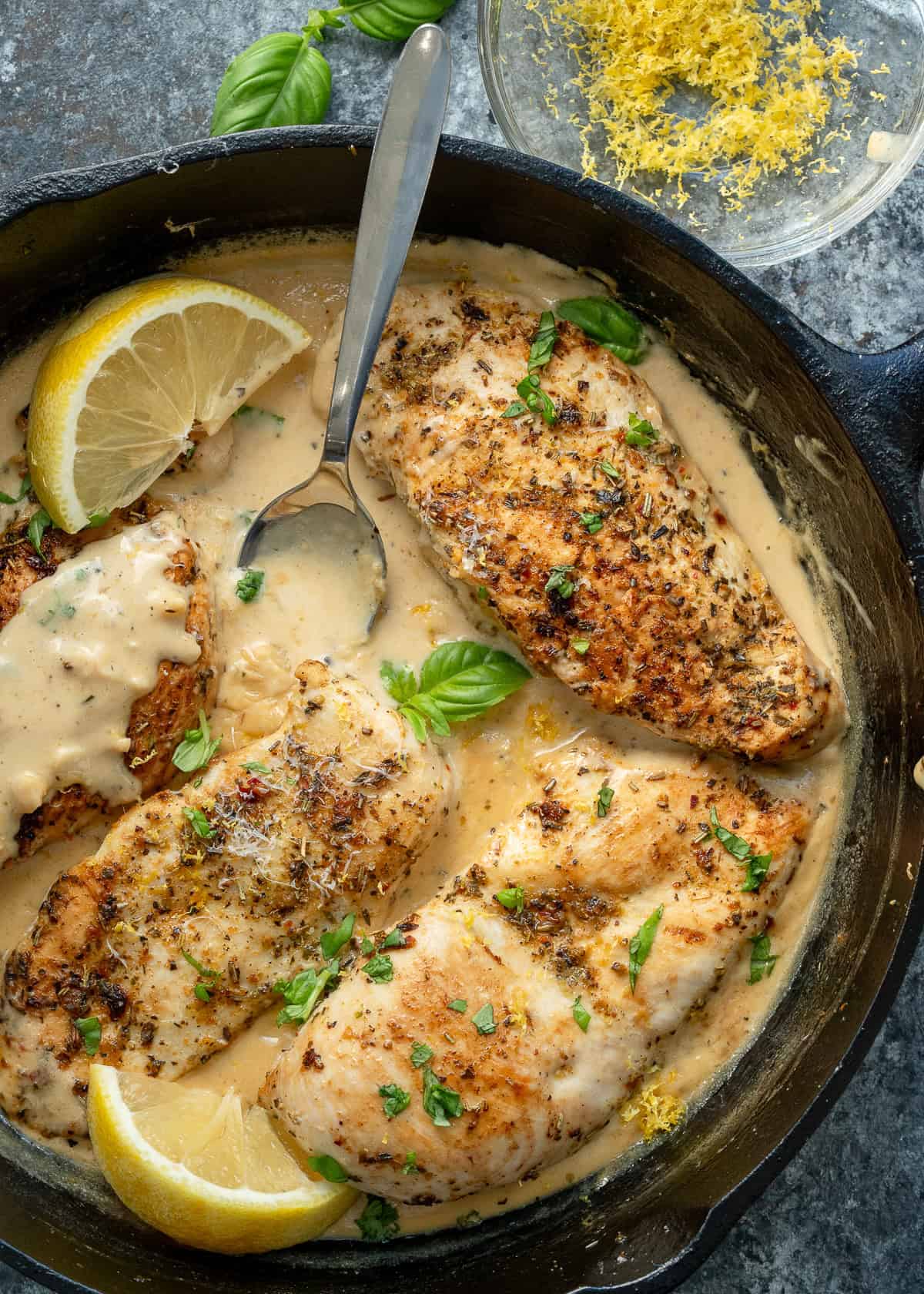 lemon chicken in creamy sauce with a spoon in a cast iron skillet