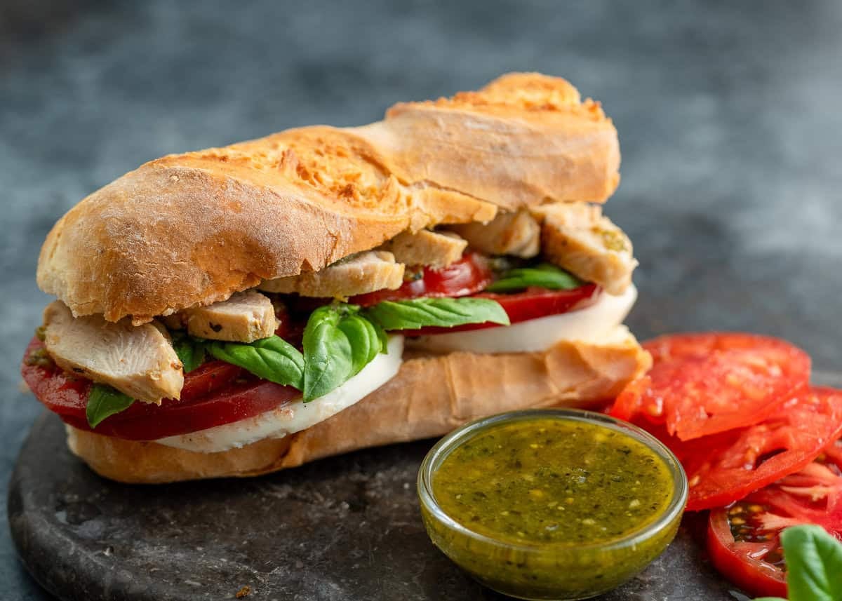 pesto sandwich and ingredients on a stone cutting board