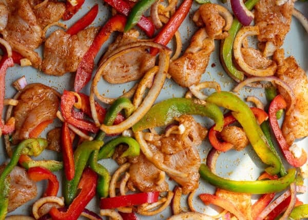 uncooked chicken fajita ingredients on a sheet pan