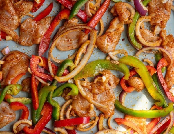 uncooked chicken fajita ingredients on a sheet pan