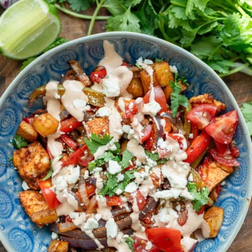 an overhead shot of a fiesta potato bowl with chipotle crema with cilantro and lime on the side