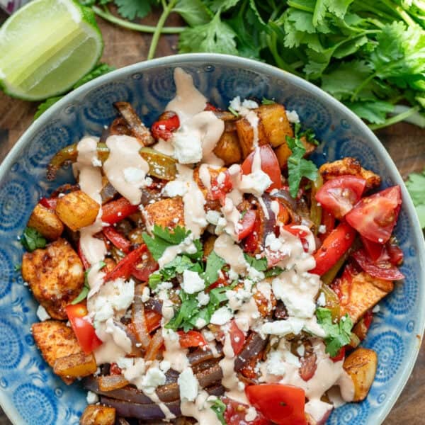 an overhead shot of a fiesta potato bowl with chipotle crema with cilantro and lime on the side