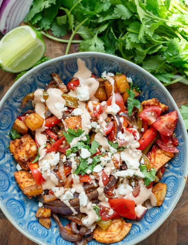 an overhead shot of a fiesta potato bowl with chipotle crema with cilantro and lime on the side
