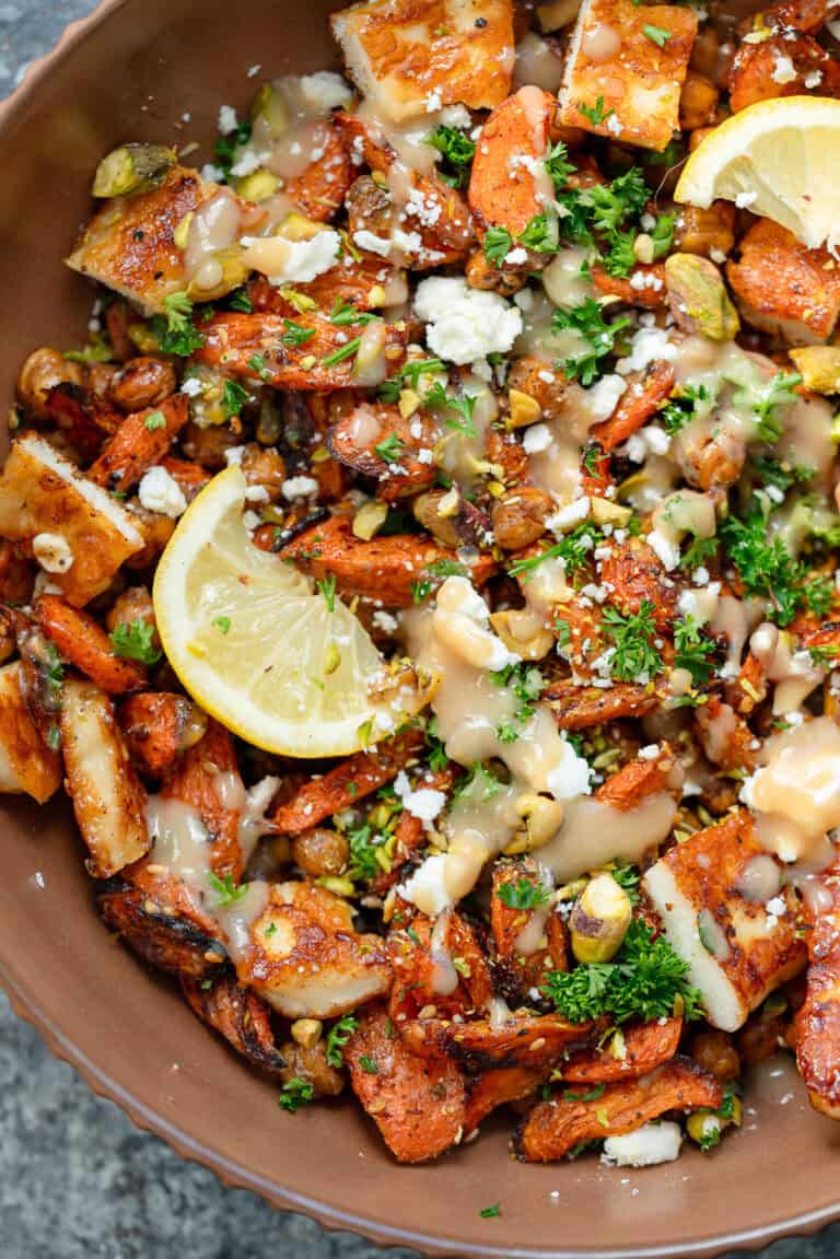 an overhead shot of hot honey halloumi salad with carrots, chickpeas and lemon in a brown bowl