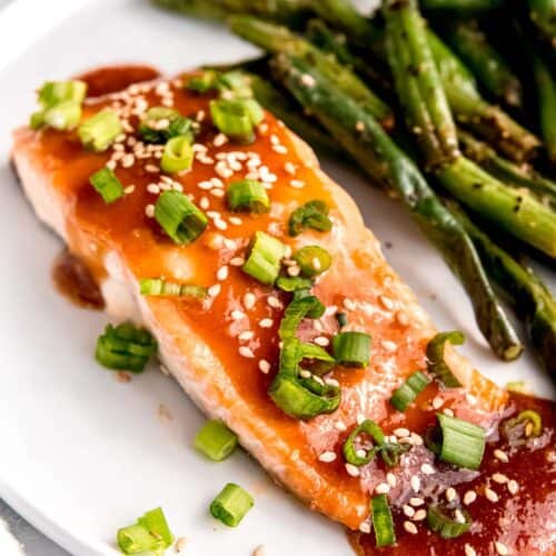overhead image of a baked salmon filet and green beans on a white plate
