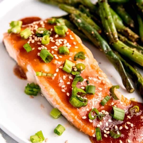 overhead image of a baked salmon filet and green beans on a white plate