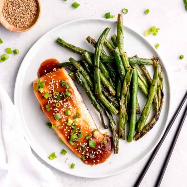 overhead image of baked salmon with teriyaki glaze on a white plate with green beans