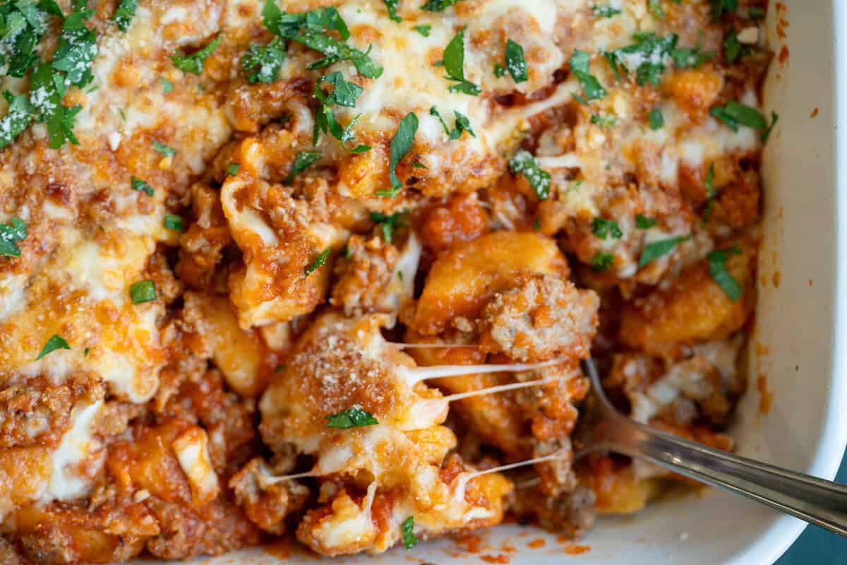 an overhead shot of gnocchi pomodoro with cheese, basil and a spoon in the corner
