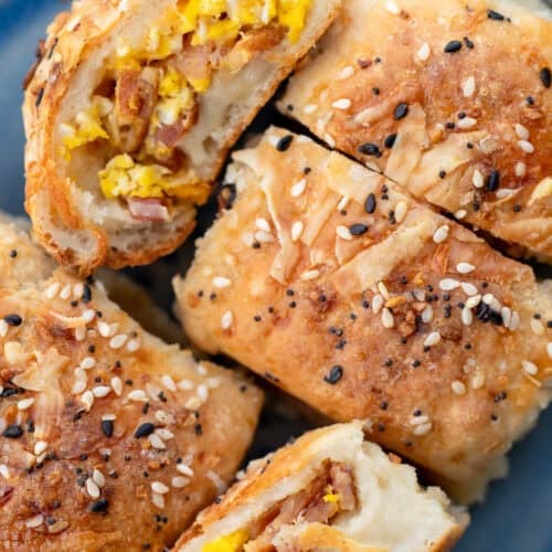 several high protein breakfast rolls on a plate, all stuffed with bacon, egg, and cheese