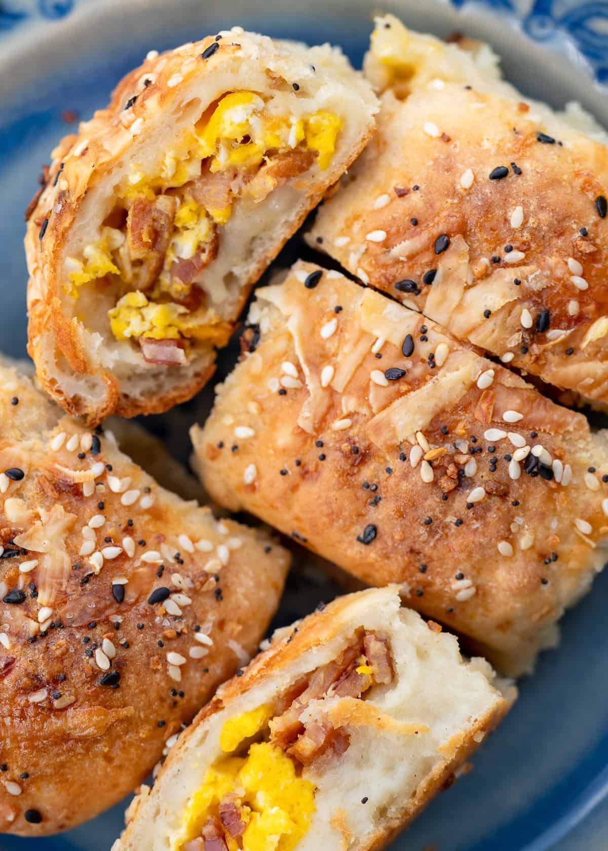 several high protein breakfast rolls on a plate, all stuffed with bacon, egg, and cheese