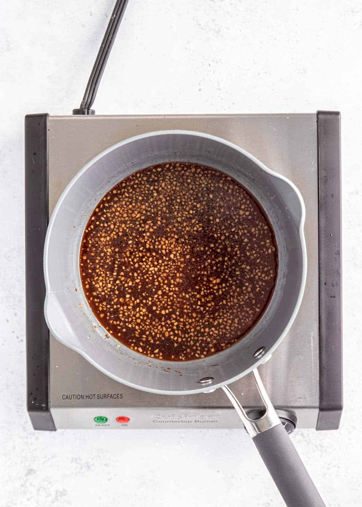 a saucepan with sesame chicken sauce